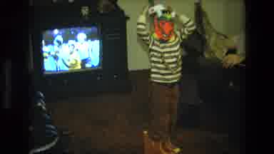 California USA (1975): A Child Wears A Mask In A Living Room In Front Of A