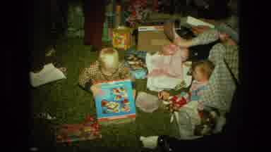 FORT WAYNE INDIANA-1976: Young Boy Unwraps Christmas Present With Infant Sibling