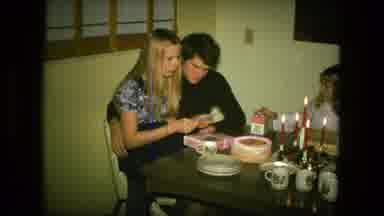 Fort Wayne Indiana (1976): People Gathered By Dining Table As Woman Opens Up