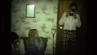 Fort Wayne Indiana (1976): Man Pretends To Take A Photo As The Other Man Unpacks
