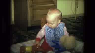 Fort Wayne Indiana (1976): An Infant Wearing A Blue Bib Plays With A Toy Dog