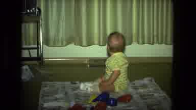 Fort Wayne Indiana (1976): Baby With Toy In Mouth Looking Around And Slapping Knee