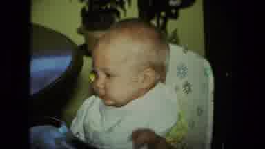 Fort Wayne Indiana (1976): Baby Being Feed In Highchair And Waving With One Hand