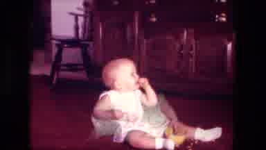 Fort Wayne Indiana (1976): Baby Wearing White Shirt Sits On Floor Eating Snacks