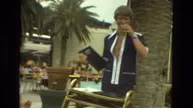 Las Vegas (1978): Man Wearing Blue Shirt Drinks From Clear Cup While Holding Black