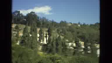 Granada Spain (1978): Partly Cloudy Blue Sky Tree Covered Cliff Next To Buildings