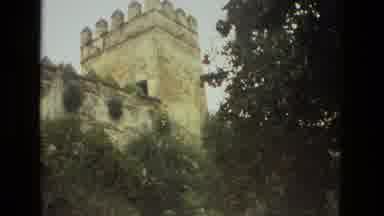 Seville Spain (1978): A Stone Tower Behind Some Leafy Trees And Well Trimmed
