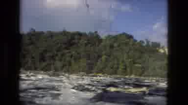 Manaus Brazil (1979): A Fast-Moving River Rushes By As Green Trees Sit On Its