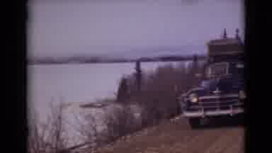 Alaska (1946): Car With Luggage On The Roof Parked On The Road Next To A Large