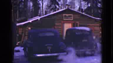 Alaska (1946): Classic Black Car Idling Outside Of Log Cabin Next To Parked Car