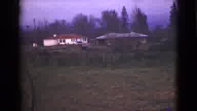 Alaska (1946): 2 Houses In The Distance Of A Wooded Area One White With A Red Roof