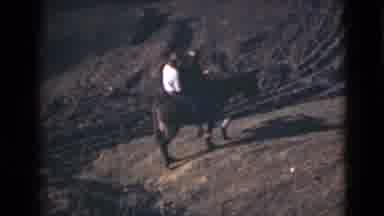 Alaska (1946): Two People Riding A Donkey On A Dirt Path In The Sunshine