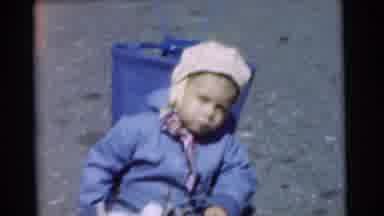 Chatham New Jersey (1951): A Child Wearing A Blue Coat And A White Hat Sits On The
