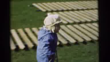 Chatham New Jersey (1951): Toddler In Cap And Jumpsuit Walks Across Grass Lawn To