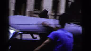 New York City (1956): Man Wearing Black Pants Runs Down Street Between Parked Cars