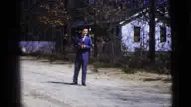 New York City (1956): Man Wearing Blue Suit Stands Next To White House On A Sunny