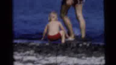 NEW YORK CITY-1958: A Little Boy In Red Shorts Splashing At The Water's Edge