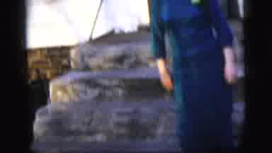New York City (1958): A Woman Wearing A Blue Dress Walking Out Of A House