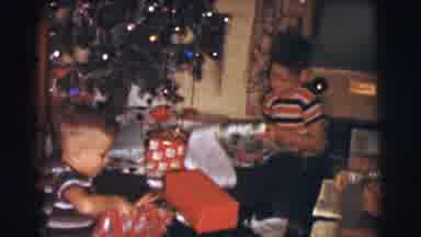 Clarkdale Arizona (1961): Two Boys Are Unwrapping Gifts Under A Decorated