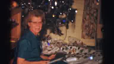 Clarkdale Arizona (1961): Woman Opens Christmas Present Near Decorated Christmas