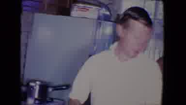 Salton Sea California (1961): Man Brings Food To Table While Mother Feeds A Child