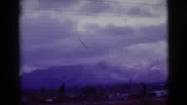 Clarksdale Arizona (1968): Clouds Hanging Above A Snow Covered Mountain Range