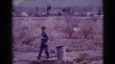 Clarksdale Arizona (1968): Boy Walking In A Flat Dirt Field With Something In His