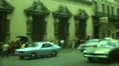Yucatan Mexico (1973): Cars Drive And Pedestrians Walk On A Busy City Street