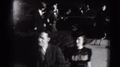 Joliet Illinois USA (1941): Man And Woman Walk Past Black Car On A Bright Sunny