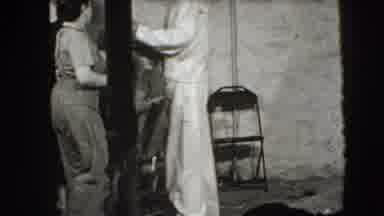 Joliet Illinois USA (1941): A Group Of Men And Woman In A Room Walking Around Near