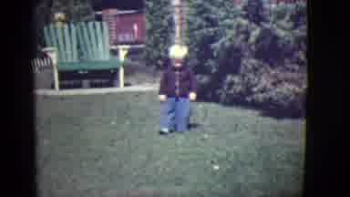 East Orange New Jersey (1946): Toddler Wearing Blue Pants Waves At Camera On Green
