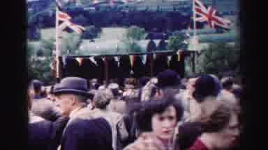 United Kingdom (1952): Crowd Of People Stand And Talk In Front Of A Stall Between