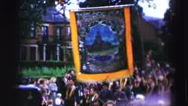 United Kingdom (1952): People Carrying Blue And Yellow Banner In Parade On A Clear