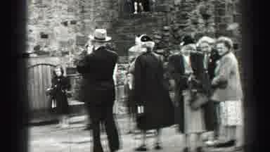 United Kingdom (1952): People Looking At Wooden Shed On A Cloudy, Windy Day