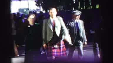 United Kingdom (1952): Men In Kilts Walking Arm In Arm With Women Down A City