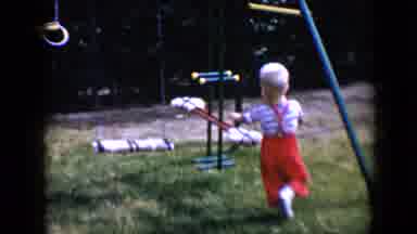 Tucson Arizona USA (1958): A Young Boy In Red Overalls Plays On A Swing Set While