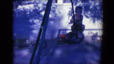 Tucson Arizona USA-1958: Boy Wearing Tan Shorts Swings On Backyard Swingset On A