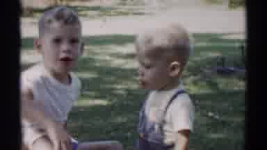 Disneyland California (1959): Boy Wearing White Shirt Sits On Grey Blanket Chewing