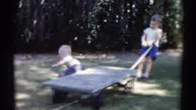 Disneyland California (1959): Boy Wearing Blue Shorts Tries Pulling Grey Dolly On
