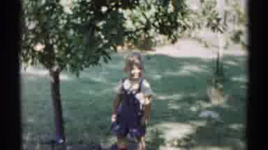 Disneyland California (1959): Child Wearing A Jumpsuit In A Park Holding A Piece