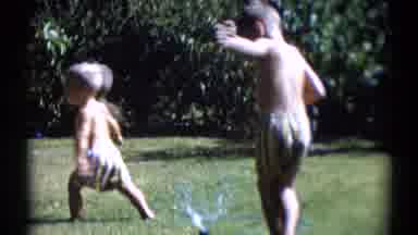 Disneyland California (1959): Boy Holds Foot Over Water Sprinkler On A Bright