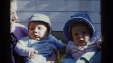 Gary Indiana USA (1961): Two Babies Sitting Outside In Hats Being Held By An Older