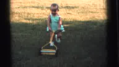 Gary Indiana USA (1961): Girl Maneuvers A Toy Lawn Mower In A Green Dress