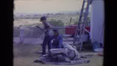 Flagstaff Arizona USA (1967): Man Watches Boy Wrangle Roll Of Metal Fencing In