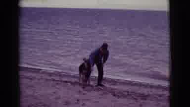 Cottonwood Arizona (1968): Man And Boy Play With Dog On The Beach On Calm Sea Day