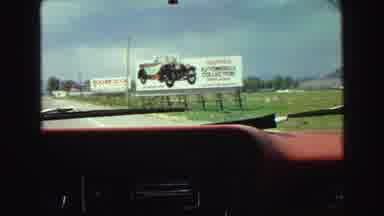 Vancouver Bc Canada (1968): Red Car Drives By Billboards Put Over Grass And