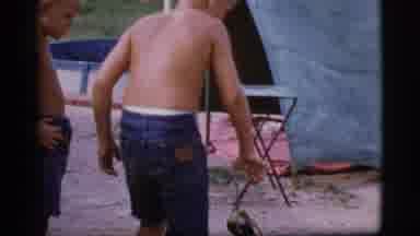 Cottonwood Arizona (1968): Boy Wearing Blue Shorts Picks Up Smoldering Wood With