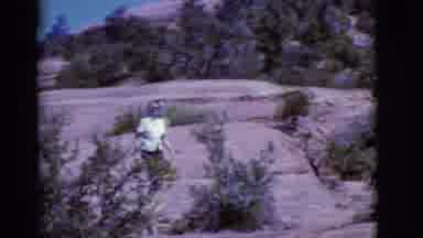 Arizona USA (1968): Woman Wearing White Shirt Walks On Rock Path Points Back At