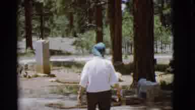 Arizona USA (1968): Woman Wearing Blue Scarf Walks To Brown Car On A Bright Sunny
