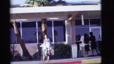 Arizona USA (1968): A Woman In A Grey Dress Holding A Jacket And Her Purse Walks